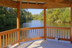 Eine Holzterrasse mit Blick auf einen von Bäumen gesäumten Fluss.