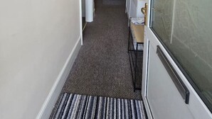 A hallway with a carpeted floor, a door with a frosted glass panel, and a staircase leading to another room. - Park Place 3 Bedroom House (North Northamptonshire)