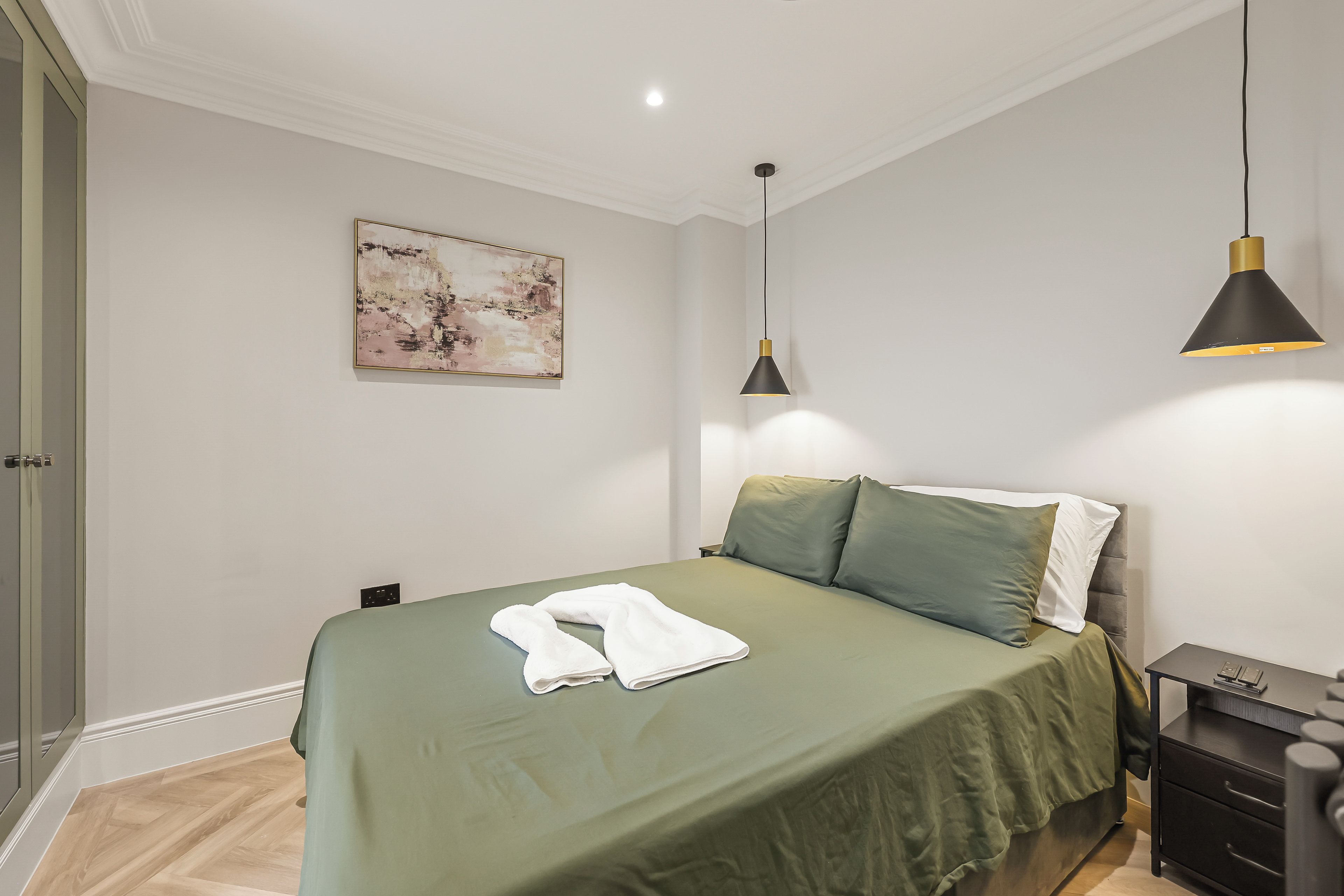 Une chambre à coucher avec un lit, une table de chevet, une lampe et un tableau au mur.