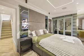 A modern bedroom with a bed, bedside tables, a mirror, and a wardrobe. - The Oakley Residence - Garden View Apartment (1) (London)
