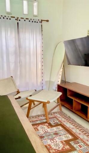 Ein Zimmer mit einem Bett, einem Sessel, einem Fernseher und einem Teppich mit Muster.