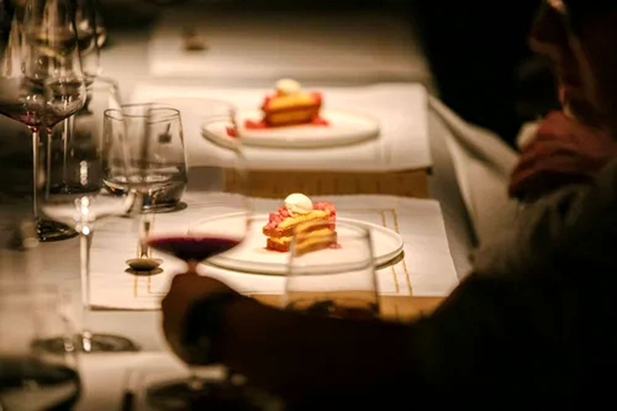A dining table with plates, glasses, and a dessert.