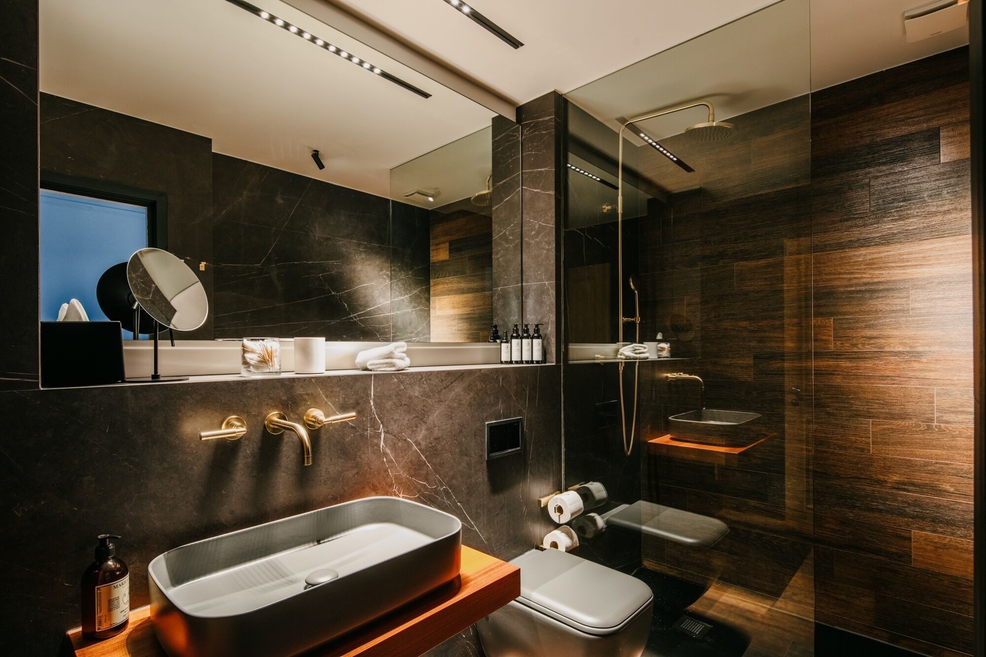 Un baño moderno con un espejo grande, un lavabo, un inodoro y una zona de ducha.