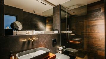 Un baño moderno con un espejo grande, un lavabo, un inodoro y una zona de ducha.