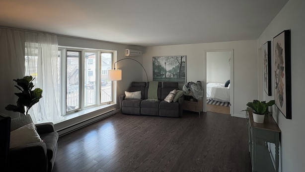 A living room with a sofa, a chair, a lamp, and a bed.