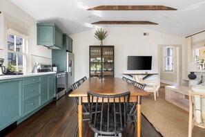 Una cocina moderna con gabinetes color turquesa, una mesa de comedor de madera y un televisor empotrado.