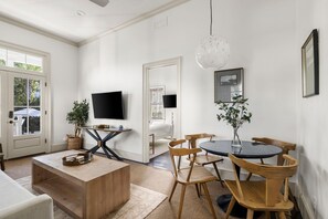 Un salon moderne avec un téléviseur, des meubles en bois et un coin repas comprenant des chaises et une table.