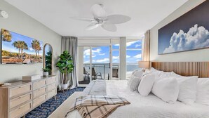 Ein Hotelzimmer mit Bett, Deckenventilator, großem Fenster mit Aussicht, Kommode und Spiegel.