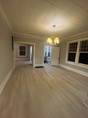 A spacious room with a wooden floor, a chandelier, and a door leading to another room. - Walking Downtown,Fabulous 1800sqft 2/2 with a loft room house huge kitchen charm (Cleveland)
