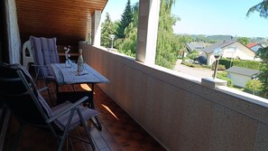 Un balcon avec une table dressée pour deux personnes, une chaise et une bouteille de champagne.