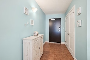 A hallway with light blue walls, a white cabinet with drawers, a black door, and a white door. - 3 Bedroom, 2.5 Bath, Sea Colony Oceanfront Condo! (Bethany Beach)