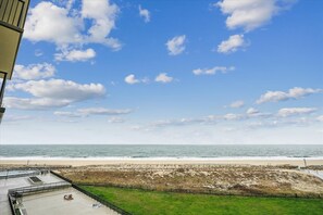 A beach view with a clear sky, a sandy beach, and a grassy area with a fence. - 3 Bedroom, 2.5 Bath, Sea Colony Oceanfront Condo! (Bethany Beach)
