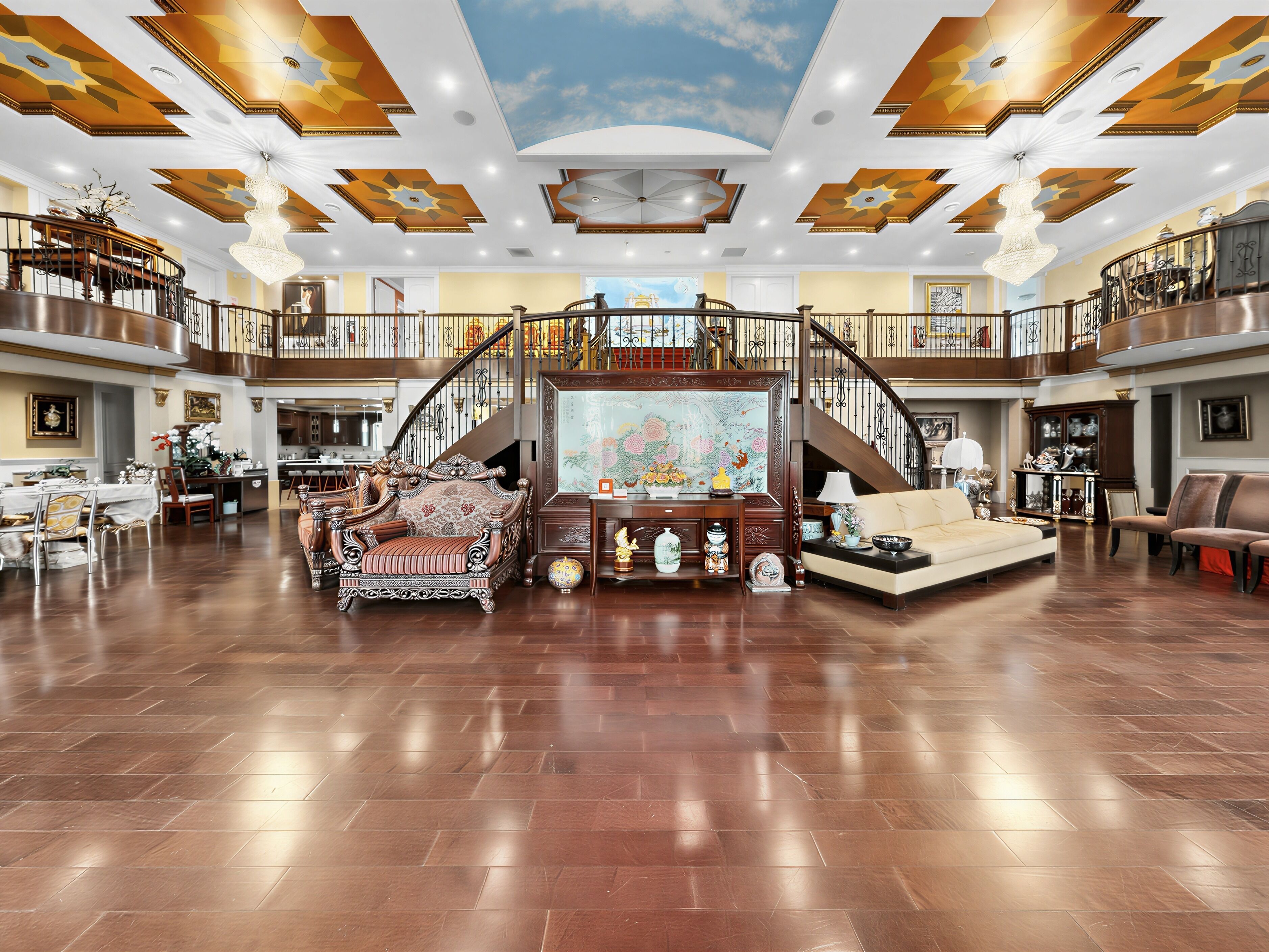 Un vestíbulo amplio con una imponente escalera, muebles ornamentados y un cuadro de gran tamaño.