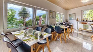 Comedor con mesas dispuestas para cuatro, ventanas amplias y vistas a zonas verdes.