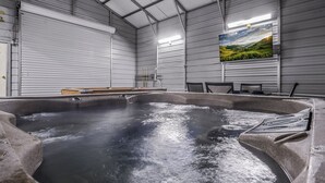 Ett bubbelbad i ett rum med ett stort fönster, väggar av metall och en platt-TV på väggen.