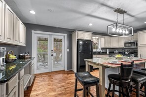 A modern kitchen with white cabinets, a black refrigerator, and a dining area with bar stools. - Remote getaway off the parkway- close to everything for 6-8 people! (Sevierville)