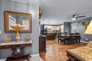 A dining area with a wooden table and chairs, a large mirror, and a ceiling fan. - Remote getaway off the parkway- close to everything for 6-8 people! (Sevierville)