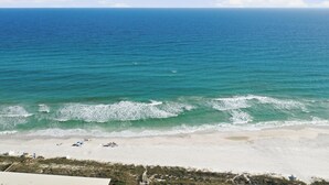 Ein Strand mit Wellen, blauem Himmel und sandigem Ufer.