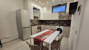 A modern kitchen with a dining area, built-in appliances, and a flat-screen TV. - Bright and quiet apartment (Pianillo)