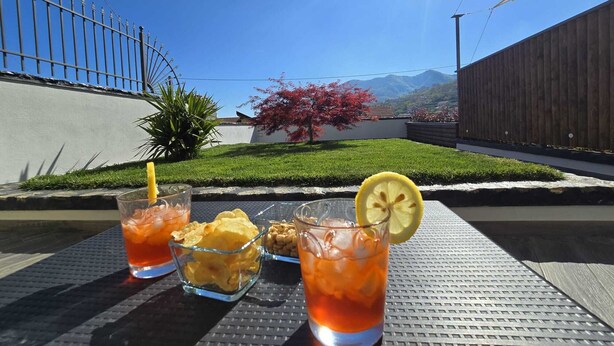 A table with drinks, snacks, and a view of a fenced yard with grass and a tree. - Bright and quiet apartment (Pianillo)