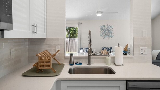 A modern kitchen with white cabinetry, a stainless steel sink, and a ceiling fan. - Harbor Hideaway|Yard + Community Pool, Near Beach (Palm Harbor)