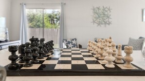 A chessboard set up for a game with pieces arranged on a table in a room with a view through a window. - Harbor Hideaway|Yard + Community Pool, Near Beach (Palm Harbor)