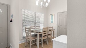 A dining area with a table and chairs, a chandelier, and a window with blinds. - Harbor Hideaway|Yard + Community Pool, Near Beach (Palm Harbor)