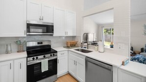 A modern kitchen with white cabinets, a black stove, a microwave, and a dishwasher. - Harbor Hideaway|Yard + Community Pool, Near Beach (Palm Harbor)