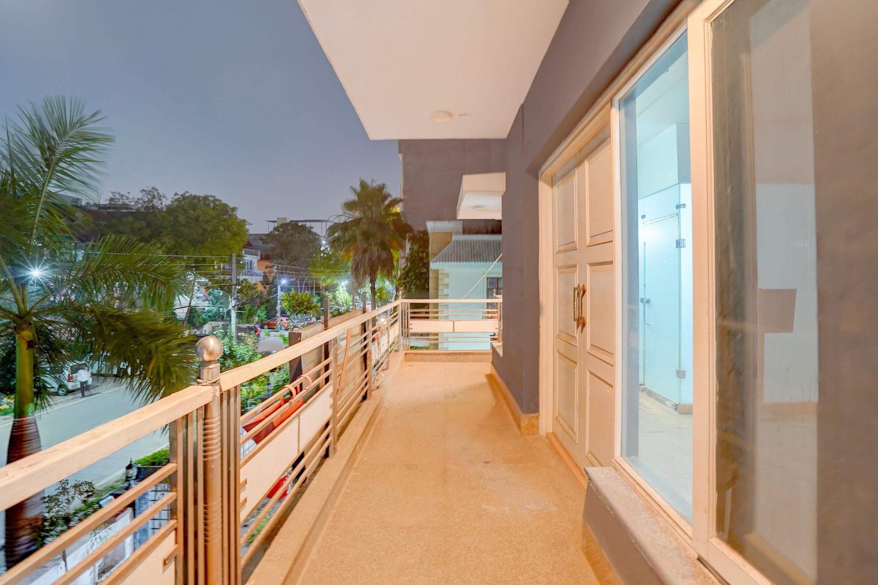 A balcony with a view of a street and palm trees, a railing, and a door with glass panels.