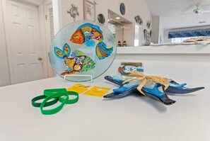 A glass art piece with colorful fish, a white table, and some blue and green items on it. - Golf Getaway- Pools- Near Beach! (Longs)