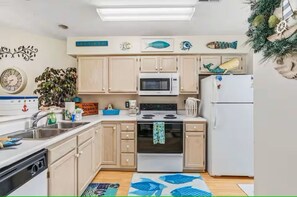 A compact kitchen with a microwave, stove, sink, and refrigerator. - Golf Getaway- Pools- Near Beach! (Longs)