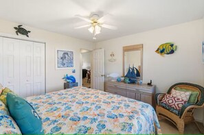 A bedroom with a bed, a dresser, a chair, a ceiling fan, and a door. - Golf Getaway- Pools- Near Beach! (Longs)