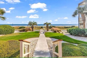 A pathway leading to a beach with palm trees and a building in the background. - Ocean Forest Villas-Beach-Pools! (Myrtle Beach)