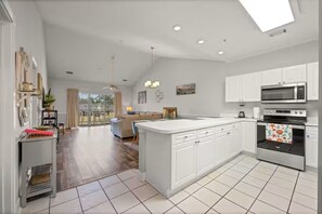 A spacious kitchen with white cabinetry, a large island, a microwave, an oven, and a dining area with a sofa and table. - Golf Resort Condo / Pool/Near Broadway Beach (Myrtle Beach)