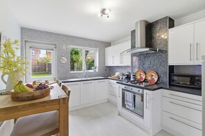 A modern kitchen with white cabinets, a granite countertop, and a built-in oven. - NEW!4BR Ideal for Contractors, Driveway, Wifi, M40 (Heathcote)