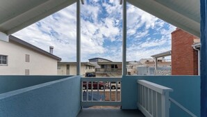 Un balcon donnant sur les maisons voisines, une entrée sécurisée par un portail et un ciel dégagé.
