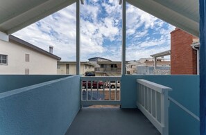 A balcony with a view of neighboring houses, a gated entrance, and a clear sky. - Perfect 2-bedroom condo & yard. Newport Beach, Balboa Pier, Fun Zone, w Parking (Newport Beach)