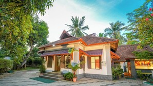 A traditional house with a tiled roof, a porch with steps, and potted plants. - POP Tavern Pool Villa by VOYE HOMES (Kovalam)