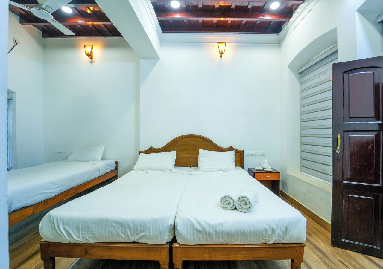 A double bed with two pillows, a nightstand with a cup, and a wooden wardrobe.
