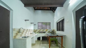 A compact kitchen with a sink, stove, and dining table. - POP Tavern Pool Villa by VOYE HOMES (Kovalam)