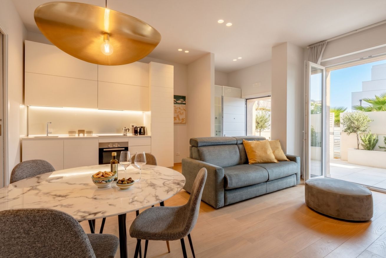 Un salon moderne avec un canapé gris, une table ronde en marbre et un luminaire suspendu.