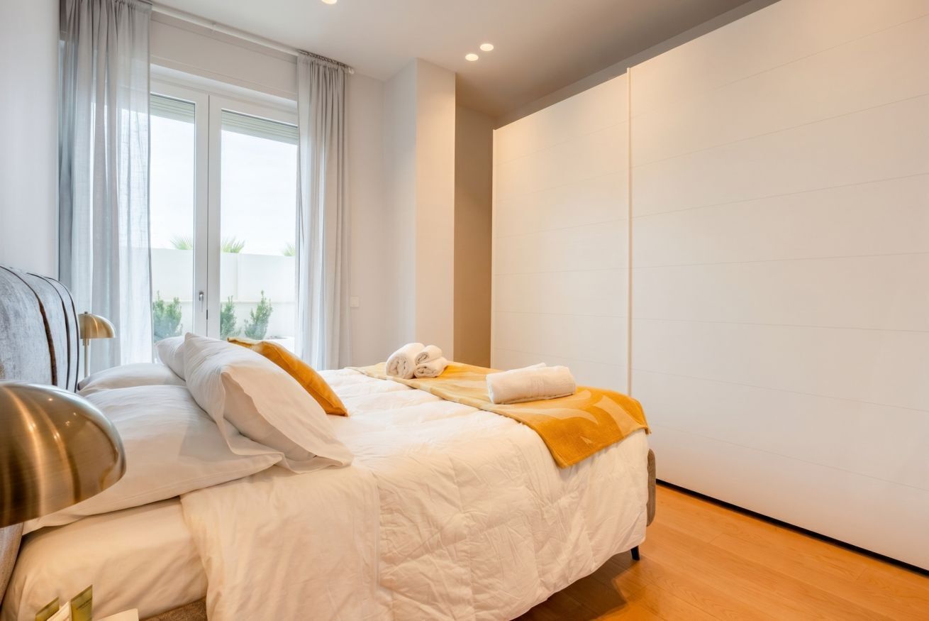 Una moderna camera d'hotel con un ampio letto, un comodino e vista sull'esterno da una finestra.
