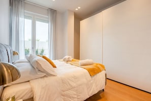 A modern hotel room with a large bed, a bedside table, and a view of the outdoors through a window. - 7Mari – A Modern and Comfortable Stay (Bari)