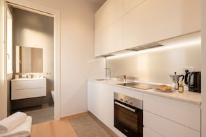 A modern kitchen with white cabinetry, a built-in oven, a sink, and a countertop with a kettle and a bottle of olive oil. - 7Mari – A Modern and Comfortable Stay (Bari)
