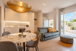 A modern living room with a grey sofa, a round marble table, and a pendant light. - 7Mari-Modern Comfort Stay (Bari)