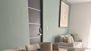 Un comedor con una mesa de madera, sillas con acolchado y un sofá al fondo.