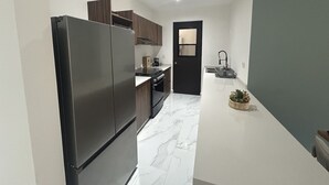 Una cocina compacta con refrigerador, estufa y pileta.