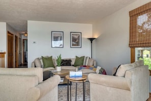 Un salon comprenant un canapé, des fauteuils, une table basse et deux tableaux encadrés accrochés au mur.