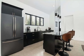 A modern kitchen with black cabinetry, a large island, and bar stools.