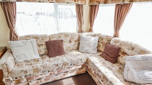 Un sofá modular con tapicería estampada, una manta marrón y una ventana con cortinas.